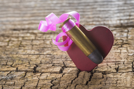Bullet with a heart decorated like a gift on a wooden background