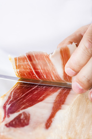 Professional cutter carving  slices from a whole bone-in serrano hamの写真素材