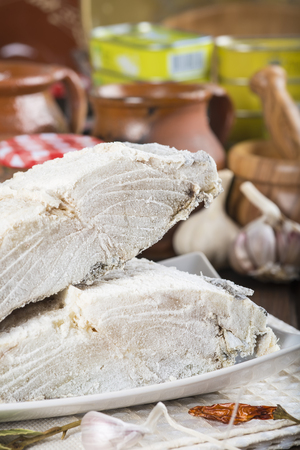 Salted cod cut with ingredients and utensils on the table of the kitchen for cookingの写真素材