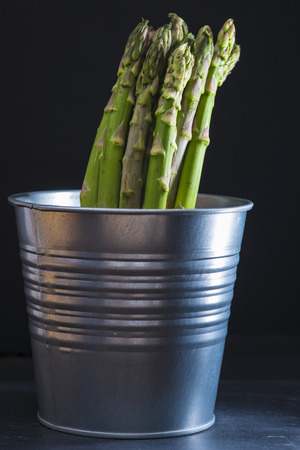 Asparagus bundle on a black background wrapped with a piece of burlapの写真素材