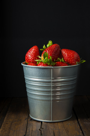 Bucket with fresh strawberries on a black backgroundの写真素材