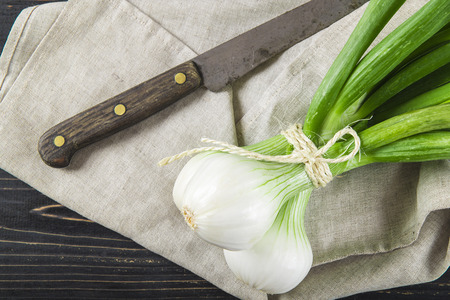 Fresh spring onions and old scissors on a black wooden backgroundの写真素材