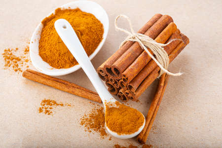 Cinnamon stick bundle and cinnamon powder spoon on a wooden table