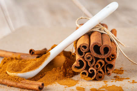 Cinnamon stick bundle and cinnamon powder spoon on a wooden tableの写真素材