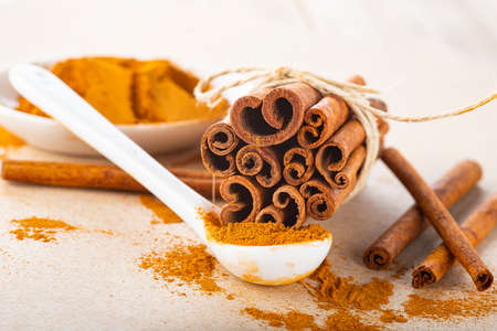 Cinnamon stick bundle and cinnamon powder spoon on a wooden tableの写真素材
