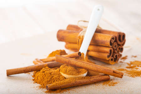 Cinnamon stick bundle and cinnamon powder spoon on a wooden tableの写真素材
