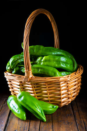 Green peppers in a basket on a wooden tableの写真素材