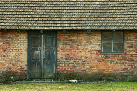 An old brick facade with its wooden door and window and the roof of old tiles in Poland.の写真素材