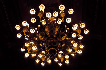 Chandelier with all its lights on on a black background.の写真素材
