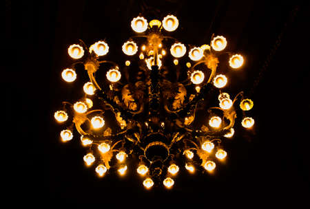 Chandelier with all its lights on on a black background.の写真素材