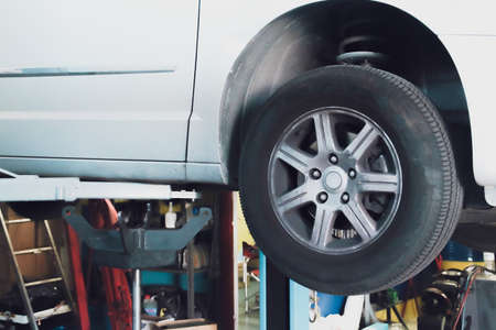 Car under repair in a mechanical workshop. Car in an elevator without wheels being repaired by a mechanic.の写真素材