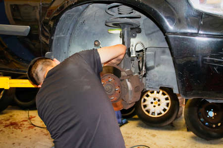 Mechanic working on the repair of a car in a mechanical workshop in Madrid, Spain.