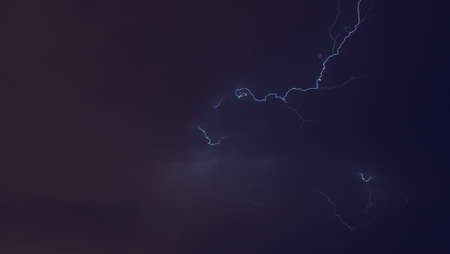 Lightning flashing over the cloudy night sky.