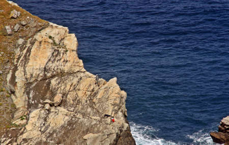Fisherman in a landscape of a rocky cliff and blue waters in the north coast of Spain.の写真素材