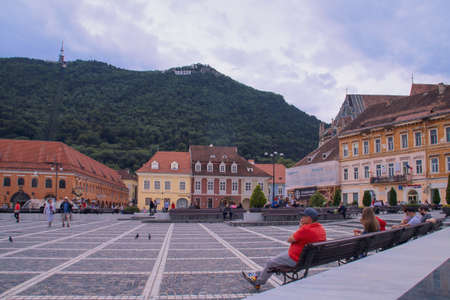 Brasov / Romania; 06/26/2018. Piata sfatului (Council Square) of Brasov. The council square with the hill and the Brasov poster on top standing out over the buildings on it.のeditorial素材