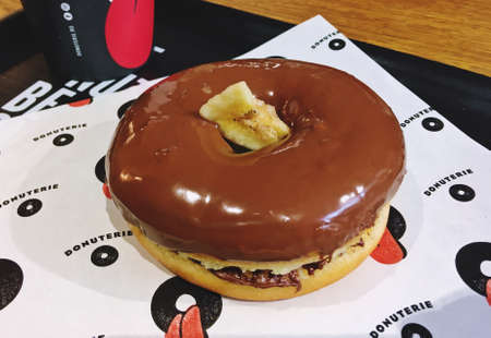 Sibiu / Romania; 06/29/2018. Chocolate donut from Donuterie Sibiu patisserie. An appetizing and delicious donut filled with chocolate and served to eat in the same restaurant.のeditorial素材