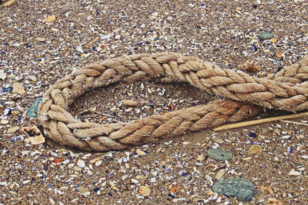 An old rope on the sand. Close-up of an old dirty and weathered rope.