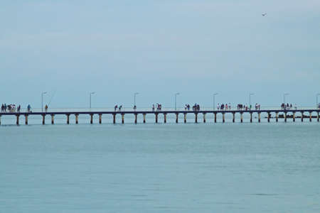 People strolling on the pier of Mamaia Beach in Constana, Romania. A long wooden pier where you can...