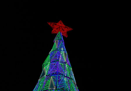 Christmas tree in the Puerta del Sol square in Madrid, Spain. Artificial Christmas tree made of lights illuminated at night and topped with a red star.の写真素材