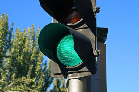 Green traffic light on San Modesto street in Madrid, Spain. Close-up of green traffic light for cars with a blue sky in the background.の写真素材