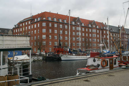Copenhagen, Denmark; 02 14 2016. Boats, houseboats, boats used as houses and buildings on a cloudy winter day. in the port of Copenhagen. Canals and colorful facades of the city.のeditorial素材
