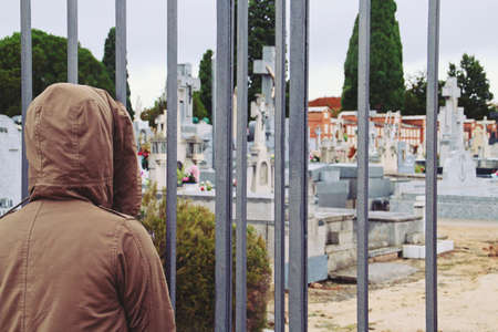 A young woman with her back turned in the Fuencarral cemetery in Madrid, Spain. Woman sheltered and...