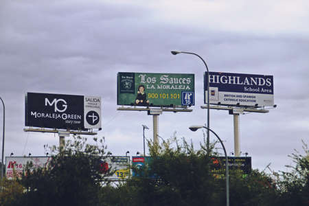 Alcobendas, Spain. 10 27 2018. Advertisements of different companies and businesses visible from the road. Giant billboards from the A1 motorway in the La Moraleja neighborhood.のeditorial素材