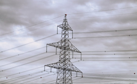 High voltage towers to conduct electricity. Picture taken on a cloudy day where the silhouette stands out against the dark sky.の写真素材