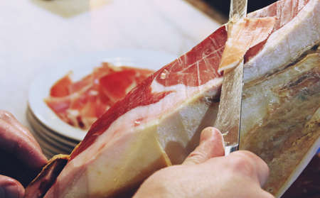 Hands of a professional cutting Iberian ham. Iberian ham, delicious and traditional product of the Spanish culture made from the Iberian pig.の写真素材