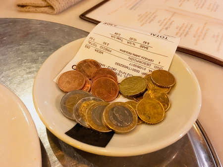 Madrid, Spain; 06 01 2017. Cash register ticket and payment in euro coins. A restaurant bill waiting to be collected by the waiter.のeditorial素材