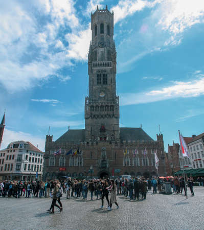 Bruges, Belgium; 04 28 2016. Belfry of Bruges in the Market Square. Tourists in the Square visiting the city.のeditorial素材