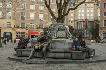 Brussels, Belgium; 04 28 2016. Charles Buls fountain in Rue du marchÃ© aux Herbes (English: Market Street Herbs). People resting sitting on the benches that surround the fountain.のeditorial素材