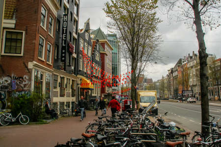Amsterdam, Holland; 04 30 2016. Nieuwezijds Voorburgwal Street in Amsterdam with orange decorations in the festivities of the Queen's day. Amsterdam cityscape with its many bicycles.のeditorial素材