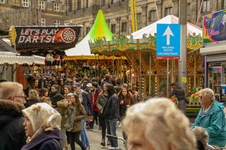 Amsterdam, Holland; 04 30 2016. Dam Square or Dam is a town square in Amsterdam, the capital of the Netherlands. Crowd and fairground attractions in Dam Square on the feast of the day of the queen.のeditorial素材
