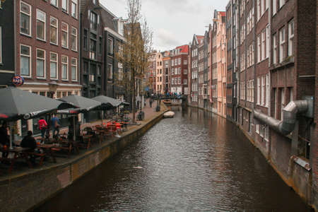 Amsterdam, Holland; 04 30 2016. Terrace bar and Canal in Korte Niezel street. The typical Amsterdam canal lined with buildings and the narrow streets on its banks.のeditorial素材