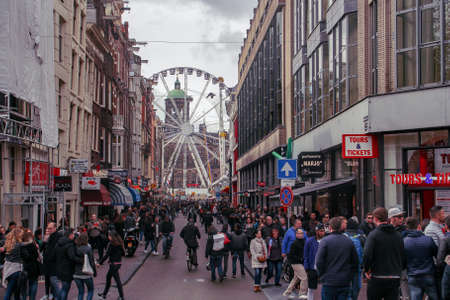 Amsterdam, Holland; 04 30 2016. Ferris wheel in Dam Square from Oude Doelenstraat (English: Oude Doelen street). Crowded street for the celebration of Queen's Day.のeditorial素材