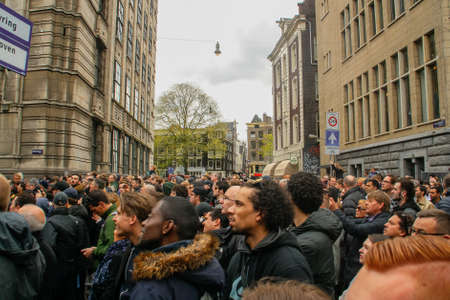 Amsterdam, Holland; 04 30 2016. An expectant crowd watching a troublemaker throwing large objects from the top of a building in the center of Amsterdam. People watching the event with expectation.のeditorial素材