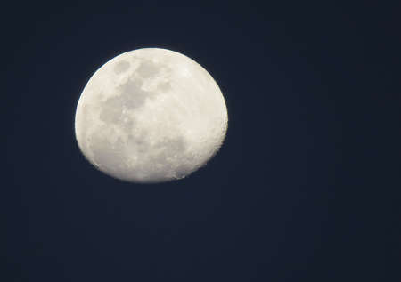 The full moon in a black sky. The brightness of the moon contrasts with the black of the night.の写真素材