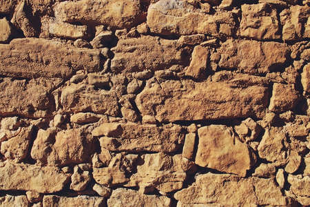 Rock wall eroded by the passage of time. Worn masonry wall where the grooves, edges and cracks...