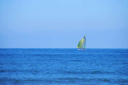 Sailing boat sailing on the horizon at Malvarrosa beach in Valencia, Spain. The Mediterranean Sea with an intense blue on a clear winter day.の写真素材