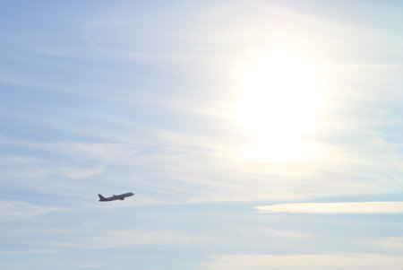 Silhouette of a passenger plane taking off from Adolfo Suarez Madrid Barajas airport. Distant and dark silhouette with the sun shining in the background in a clear sky.の写真素材