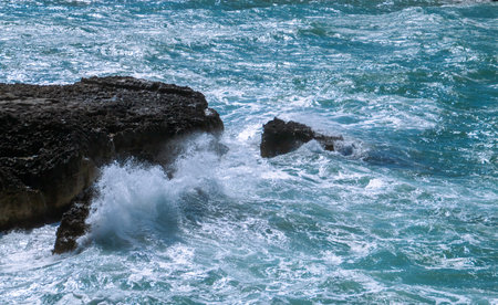 Breaking waves on the coast of Roca Vecchia in Lecce, Italy. Splashing waves of a turquoise blue...