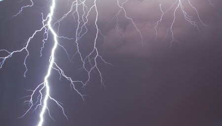 Lightning illuminating the overcast sky. A powerful lightning strike in the cloudy sky, on a dark stormy day over Madrid.の写真素材