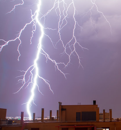 Lightning illuminating the overcast sky. A powerful lightning strike in the cloudy sky, on a dark stormy day over Madrid.の写真素材