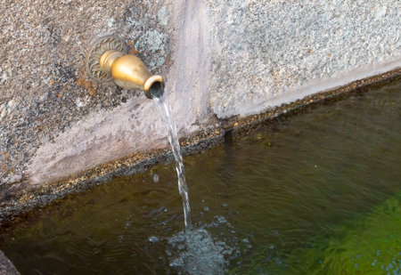 Vintage water fountain in a park, detail of a fountain with water pouring. Pilar fountain in the square of the same name, in Hoyos del Espino, Ãvila, Spain.の写真素材