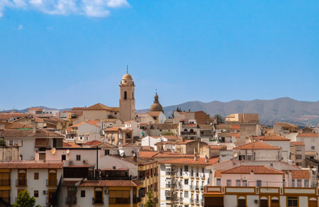 Bell tower of the church of Santa Catalina and behind that of the church of La Encarnacion de Loja. View of the bell tower and roof surrounded by residential buildings in Loja.の写真素材
