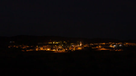 Night panoramic image of the town, El Granado, Huelva, Andalusia, Spain. Town streets illuminated by the municipality's streetlights with the church bell tower in the center.の写真素材