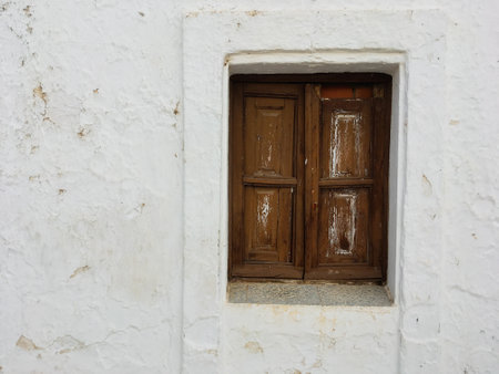 Rustic wooden window in a whitewashed stone wall in SanlÃºcar de Guadiana, Spain. Closed and...