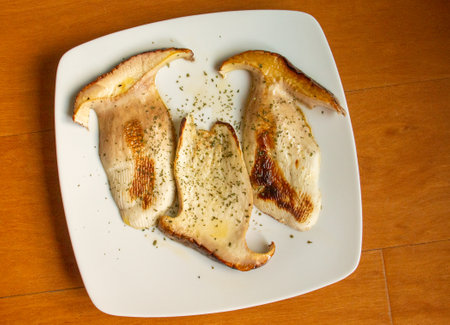 Slices of fried Boletus edulis on a white plate. Some delicious boletus cut into slices and drizzled with a little olive oil and seasoned with parsley. Madrid, Spain.の写真素材