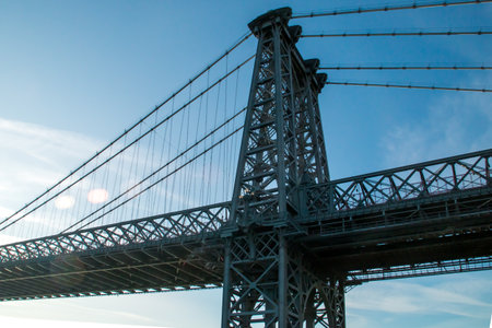 Silhouette and structure of the Williamsburg Bridge at sunrise. Pillar located on the south side of...